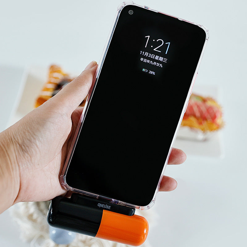 Hand holding a smartphone with a clear case, displaying the time and date on a blurred background.